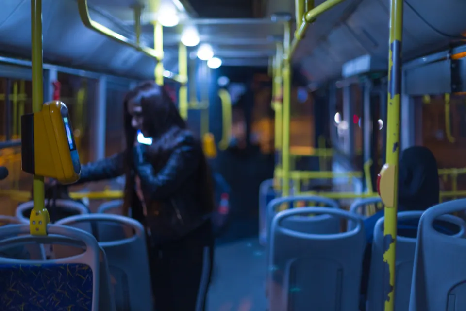Nighttime bus interior with one rider standing by door